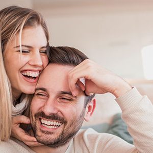 Quarantine With Your Partner. covid-19 couples help. Couple on the sofa laughing while on the laptop.