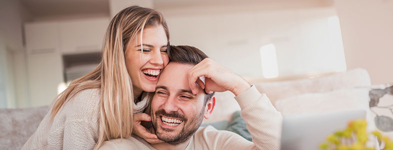 Quarantine With Your Partner. covid-19 couples help. Couple on the sofa laughing while on the laptop.