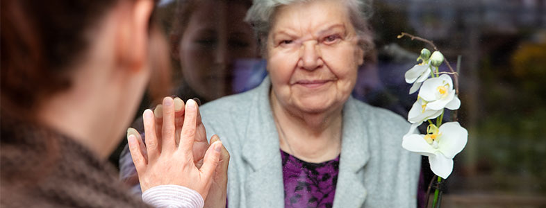 how to stay social during social distancing. Daughter seeing her mum from a glass window.