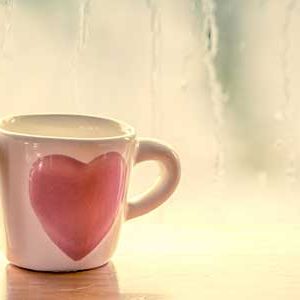 love during the coronavirus 2 heart mugs on table with rain on window in background.