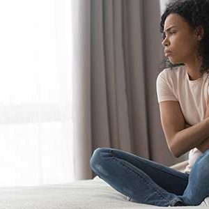 young women sat on bed struggling with mental help during coronavirus