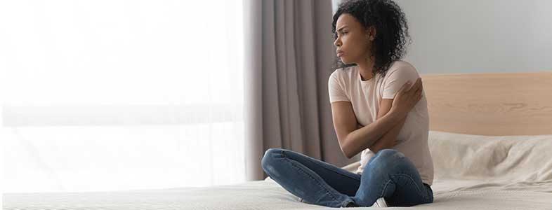 young women sat on bed struggling with mental help during coronavirus