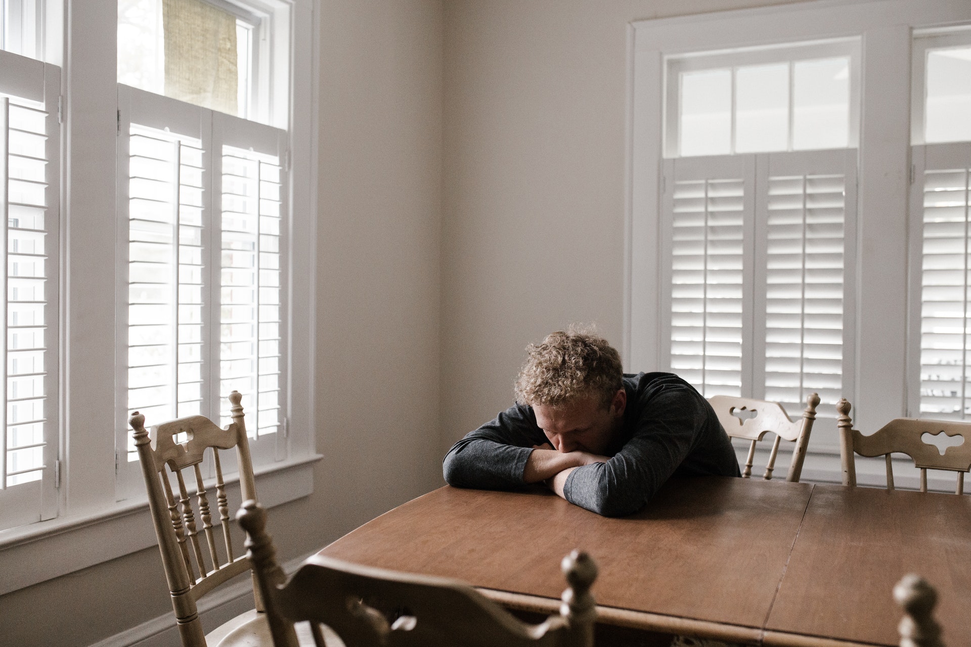 man sitting at table experiencing low mood and depression