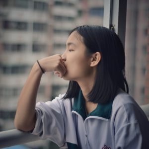 woman looking out the window with axiety