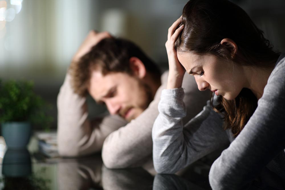 Sad couple complaining after argument in the night at home