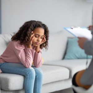 Unhappy girl listening to psychologist at meeting, thinking about her problems