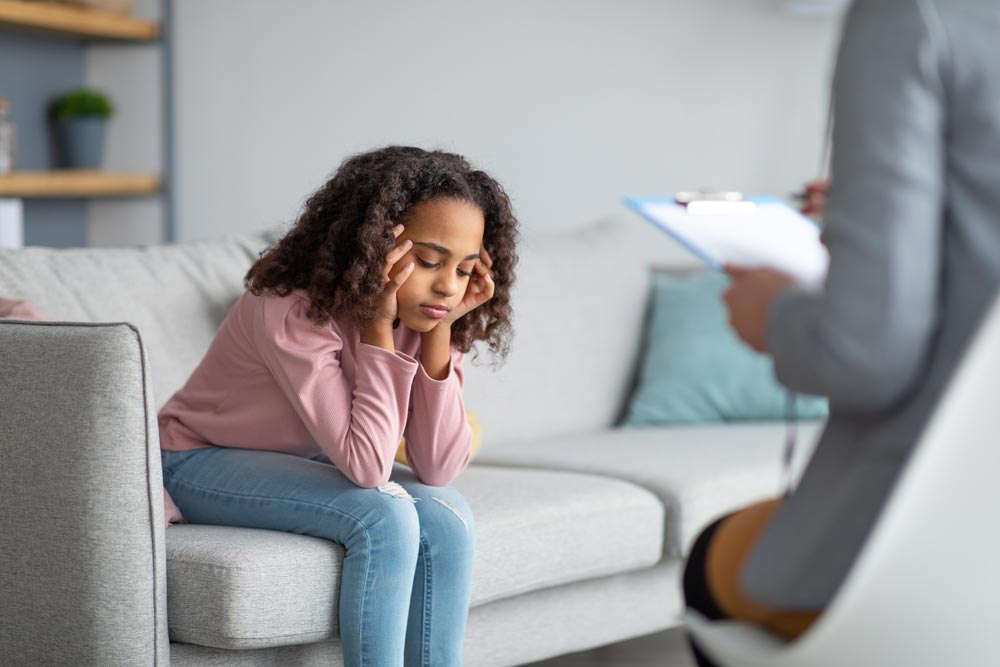 Unhappy girl listening to psychologist at meeting, thinking about her problems