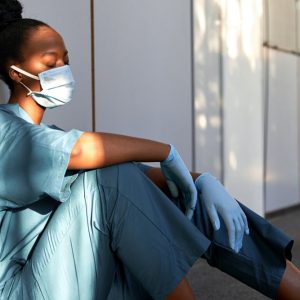 stressed nurse sitting on the floor suffering with her mental health