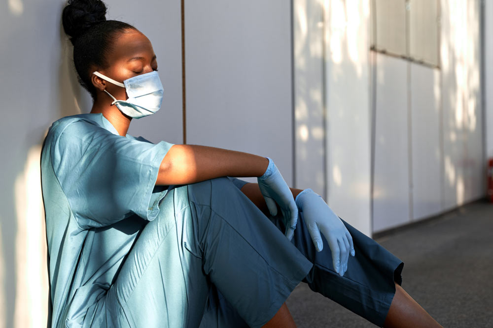 stressed nurse sitting on the floor suffering with her mental health